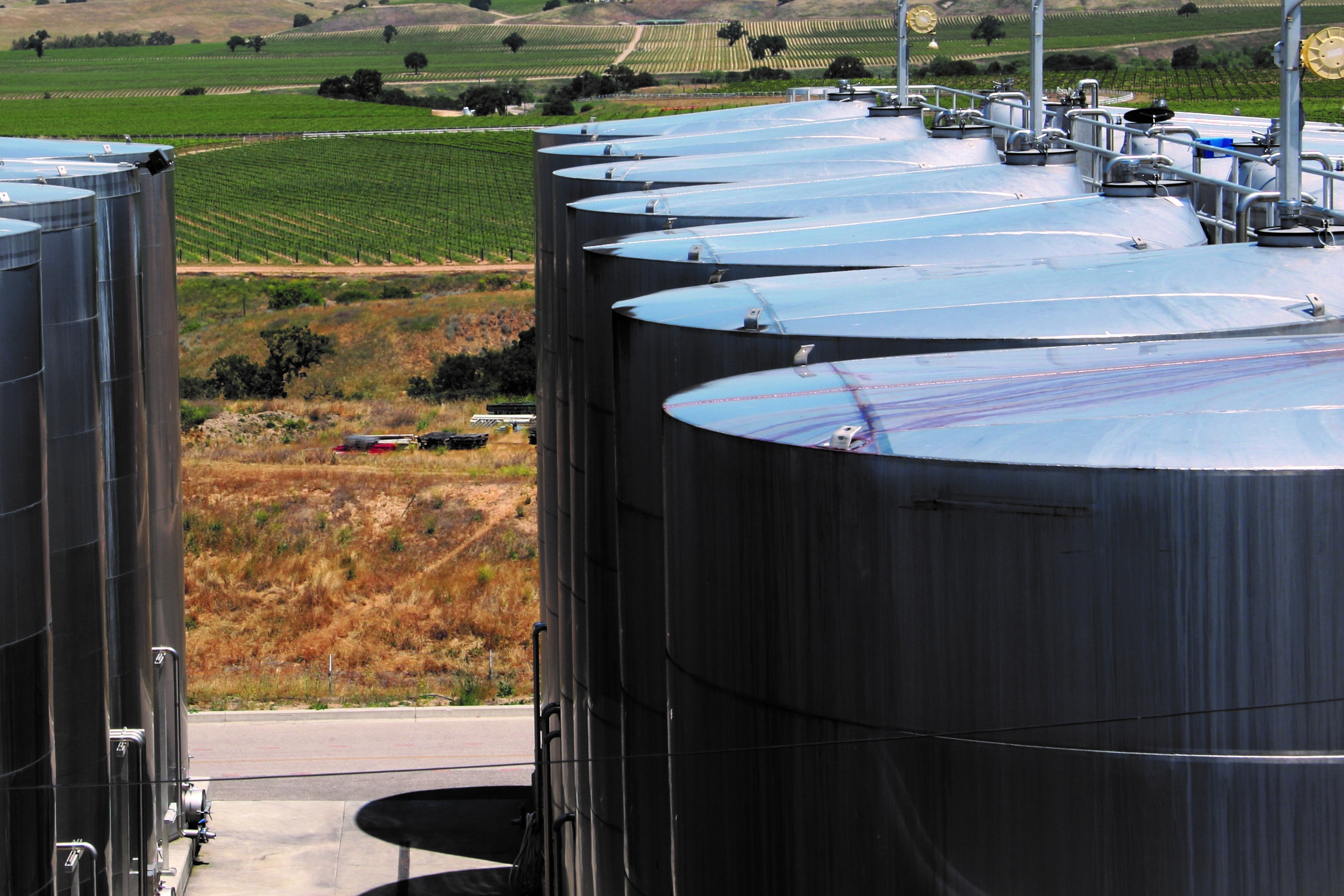 Photo of wine tanks with vineyards in background by Phil Bourke